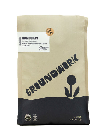 A brown and black bag of Groundwork Coffee's Regenerative Organic Certified® Honduras CAFICO whole bean coffee with a flower design and notes of red currant and brown sugar on the label.