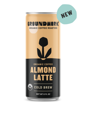 An 8 fl oz can of Groundwork Coffee Organic Cold Brew Latte with a NEW label, featuring a black and tan design with a stylized flower.