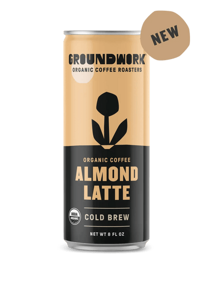 A can of Groundwork Coffee Organic Cold Brew Latte, with a black and beige design, a flower graphic, and a "NEW" label at the top right.
