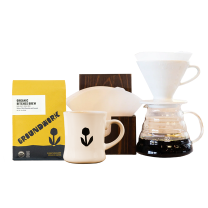 The Hario V60 Pro Bundle from Groundwork Coffee includes a bag of coffee, a white ceramic mug, and filters—ideal for the perfect pour-over experience.