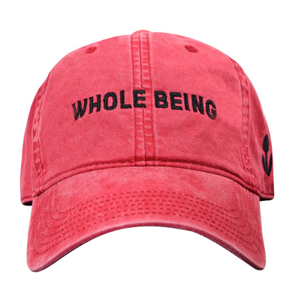 The Whole Being Dad Hat by Groundwork Coffee: red garment-dyed cotton, black “WHOLE BEING” front embroidery, small black side symbol.