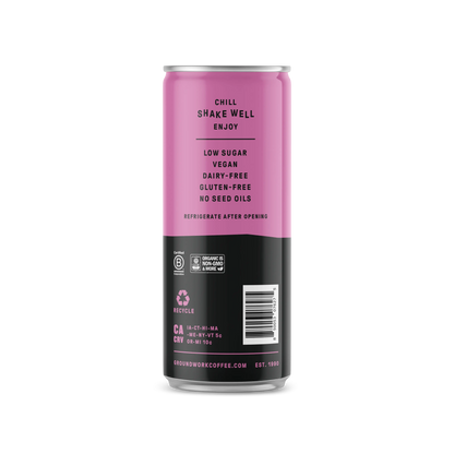 A pink and black can of Groundwork Coffee Organic Cold Brew Latte lists: low sugar, vegan, dairy-free, gluten-free, no seed oils. Chill, shake well, enjoy. Recycling info and website below.