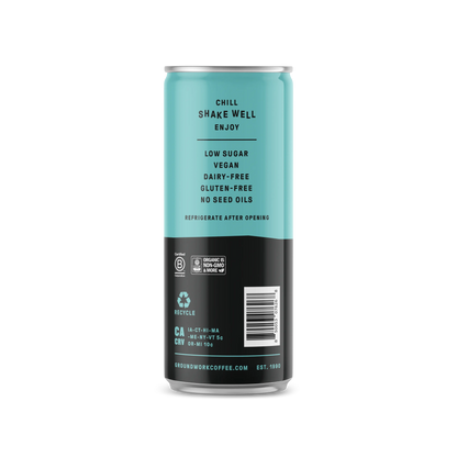 A blue and black Groundwork Coffee Organic Cold Brew Latte can lists: chill, shake well, enjoy, low sugar, vegan, dairy-free, gluten-free, no seed oils; instructions and recycling info included.
