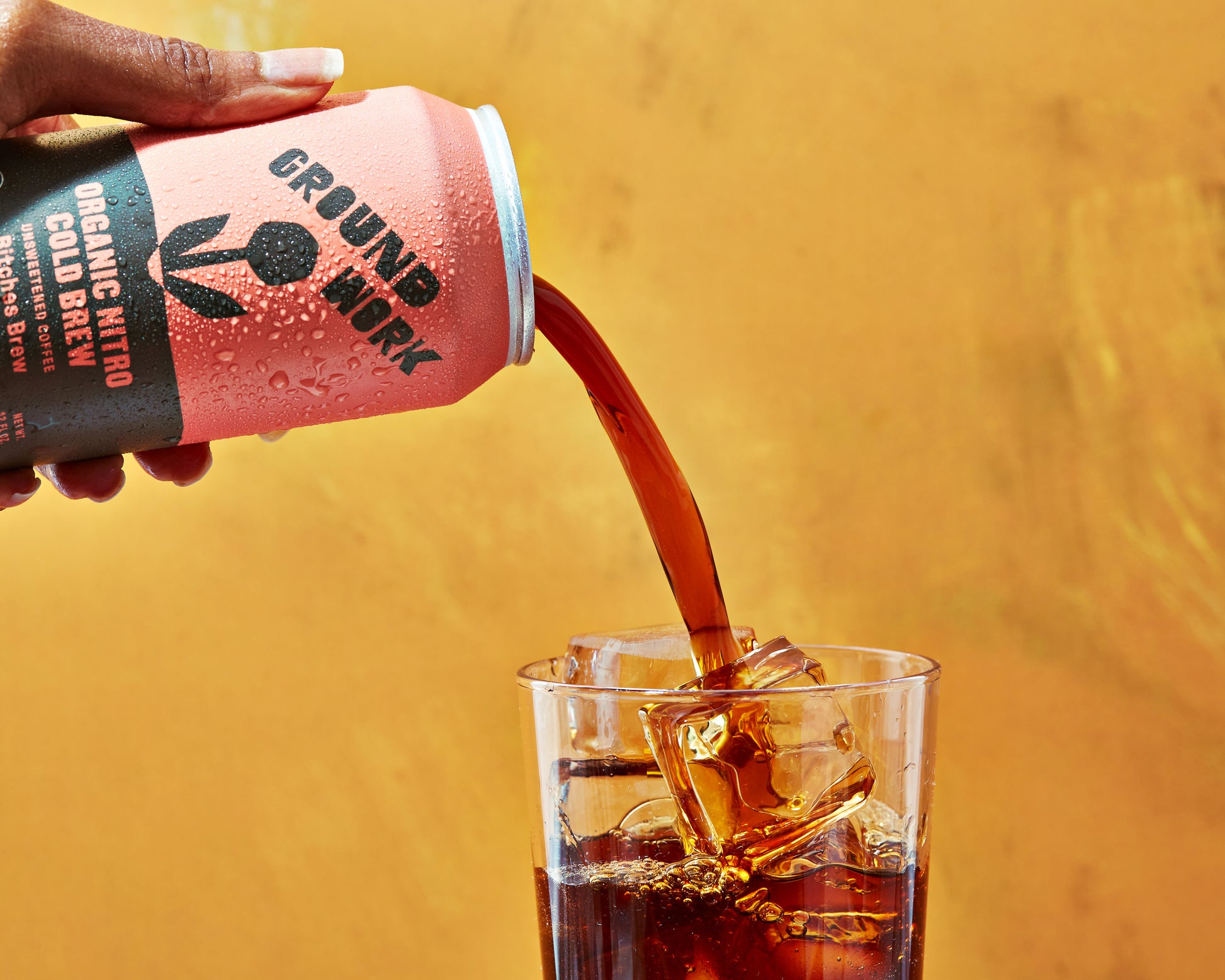 Pouring Groundwork Organic Nitro cold brew into a glass of ice